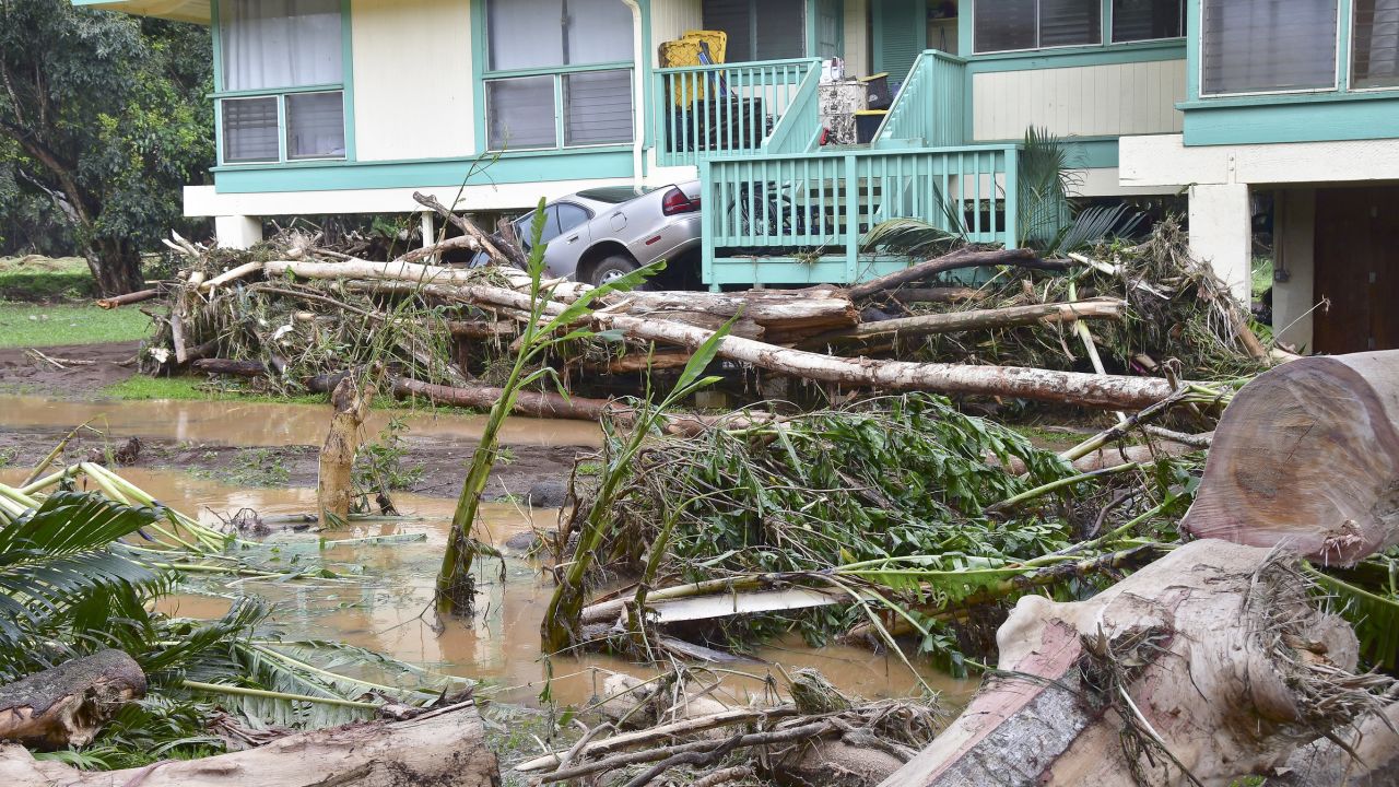 A car is wedged between a house and debris in Anahola, Hawaii, Sunday.