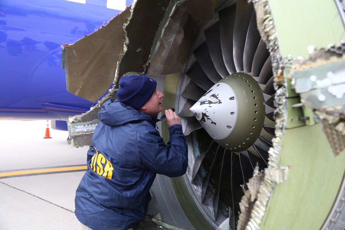A National Transportation Safety Board investigator examines the damaged engine Tuesday.