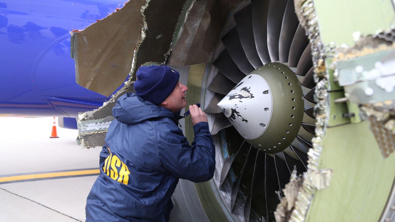A National Transportation Safety Board investigator examines the damaged engine.