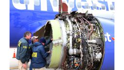 National Transportation Safety Board investigators examine damage to the engine of the Southwest Airlines plane that made an emergency landing at Philadelphia International Airport in Philadelphia on Tuesday, April 17, 2018. The Southwest Airlines jet blew the engine at 32,000 feet and got hit by shrapnel that smashed a window, setting off a desperate scramble by passengers to save a woman from getting sucked out. She later died, and seven others were injured. (NTSB via AP)