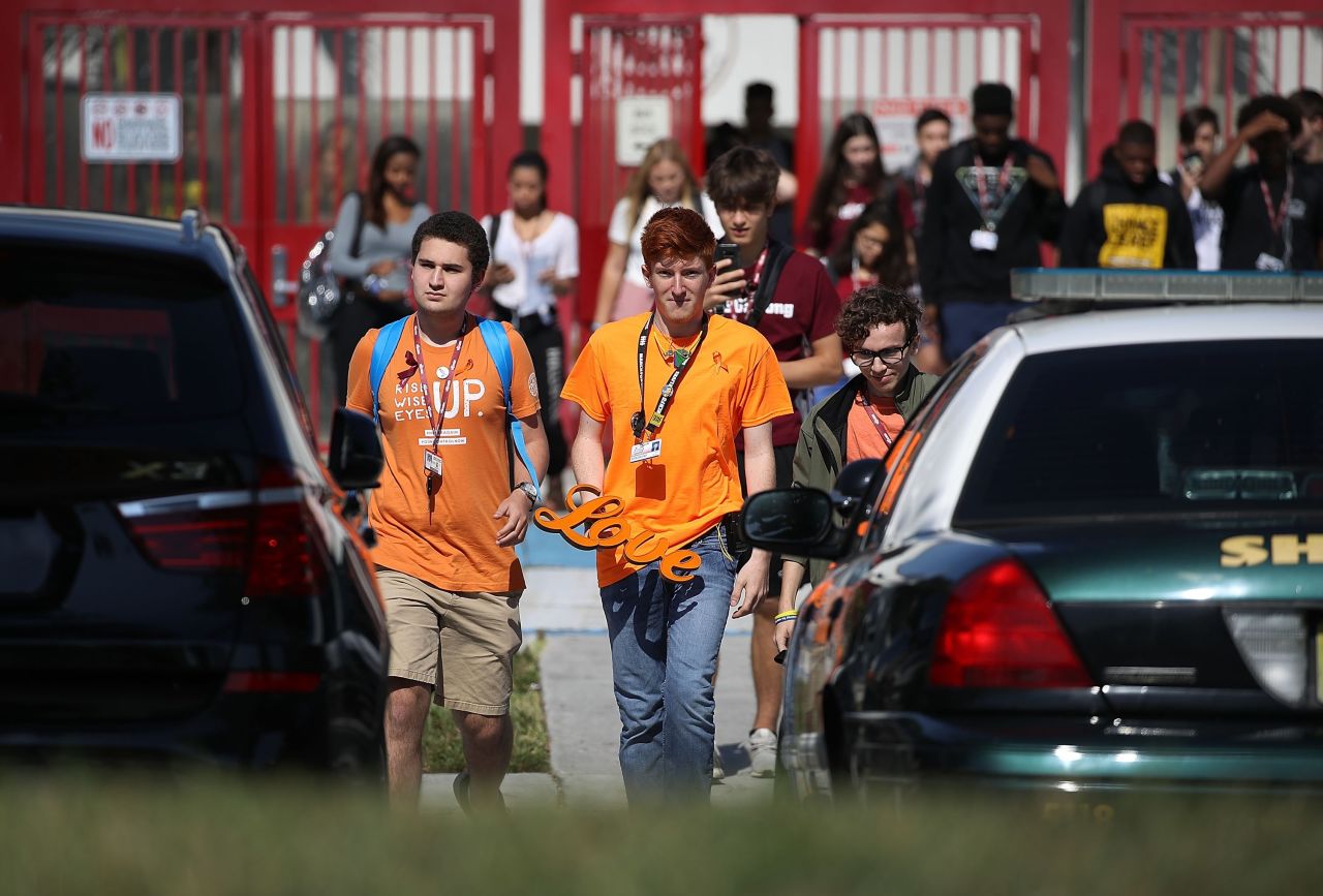 Ryan Deitsch, right, a high school senior, carries a sign that reads "love" as he joins his fellow students from Marjory Stoneman Douglas High School, where 17 classmates and teachers were killed during a mass shooting in February, for the National School Walkout in Parkland, Florida.