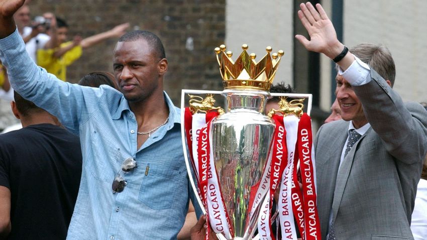 LONDON, UNITED KINGDOM:  Arsenal team captain Patrick Vieira (L) and manager Arsene Wenger wave from the open-top bus carrying the winners of the British Premier League Championship, Arsenal players and their families, on  its way to Islington Town Hall,16 May  2004, as part of the Club's victory celebration.       AFP PHOTO/ Martyn HAYHOW  (Photo credit should read MARTYN HAYHOW/AFP/Getty Images)