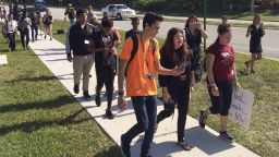 David Hogg, left, a student activist from Marjory Stoneman Douglas High School speaks to a student as they walk out of their school, Friday, April 20, 2018 in Parkland, Fla.  Another wave of student walkouts is expected to disrupt classes Friday at hundreds of schools across the U.S. as young activists press for tougher gun laws. The protests were chosen to line up with the 19th anniversary of the Columbine High School shooting, which left 13 people dead in Littleton, Colorado. At 10 a.m., students plan to gather for moments of silence honoring the victims at Columbine and other shootings. (AP Photo/Terry Spencer)