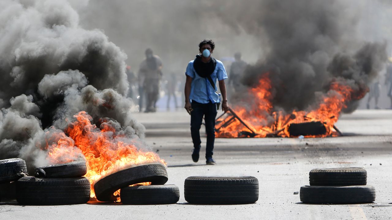 A masked protester walks between burning barricades Friday in Managua, Nicaragua.