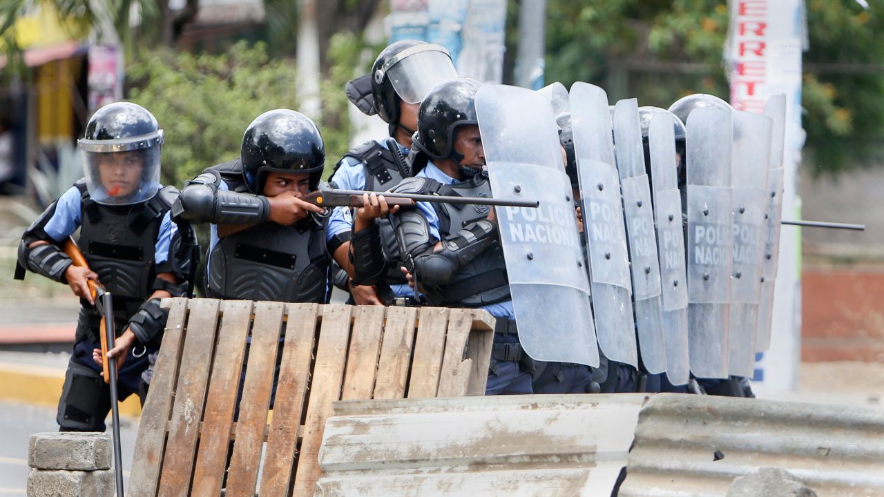 A police officer aims his weapon at students protesting social security reforms  in Managua, Nicaragua.