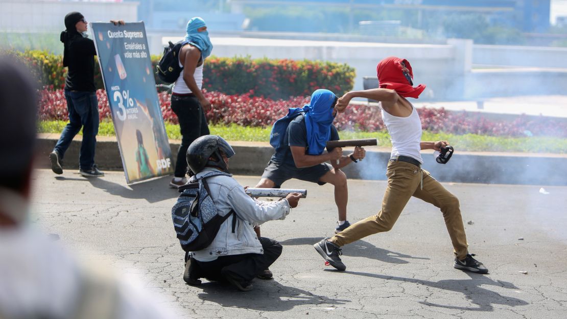 Masked protesters fire from homemade mortars at riot police in Managua, Nicaragua last week.