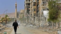  A picture taken during a Syrian army-organised tour on April 20, 2018 shows a man walking down a street past destruction in the Eastern Ghouta town of Douma on the outskirts of the capital Damascus.
