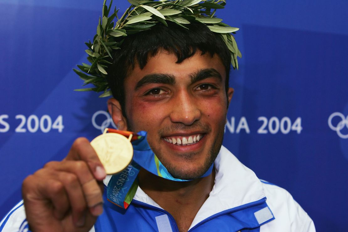 A smiling Iliadis holds the gold medal at the Athens 2004 Olympic Games. 