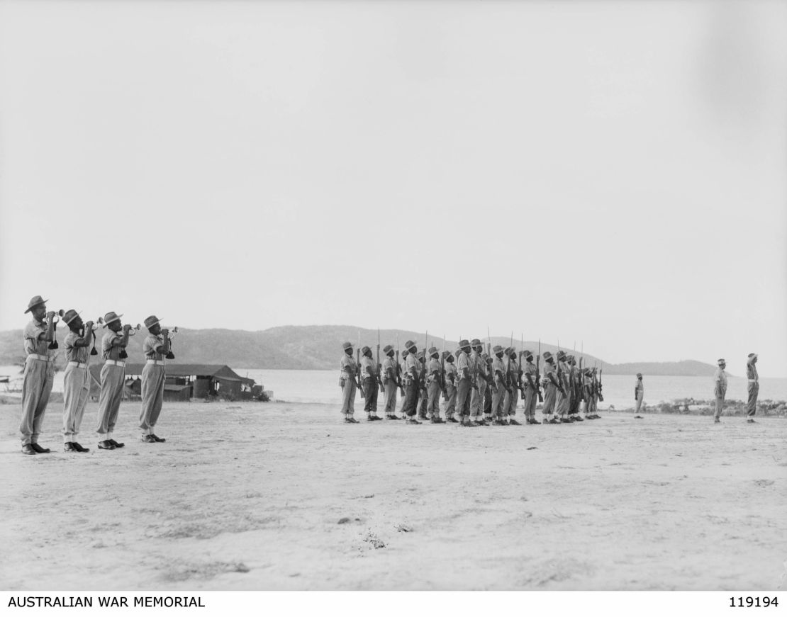 Troops of the Torres Strait Light Infantry Battalion present arms during the lowering of the colors on October 10, 1945.