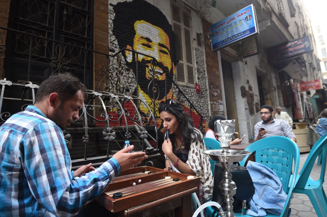 Egyptians gather at a cafe near a graffiti of Salah in Cairo.