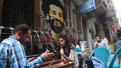 Egyptians gather at a cafe near a graffiti of Salah in Cairo.