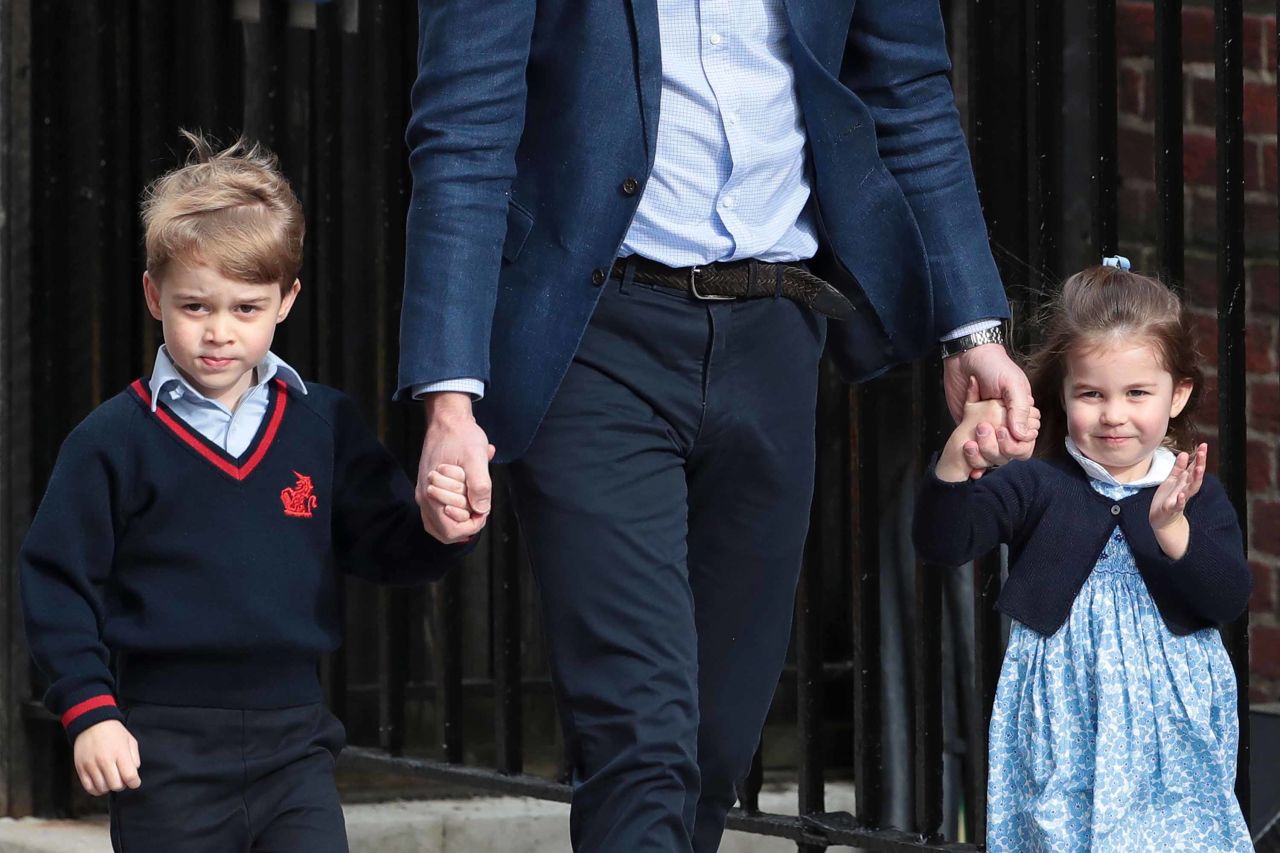 Prince William holds the hands of his other two children, Prince George and Princess Charlotte, as they visit the hospital to meet their new brother.