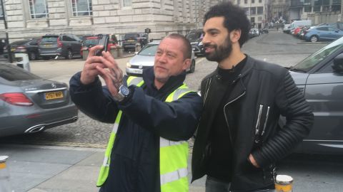 Salah pauses for a selfie with a fan while walking by the River Mersey.
