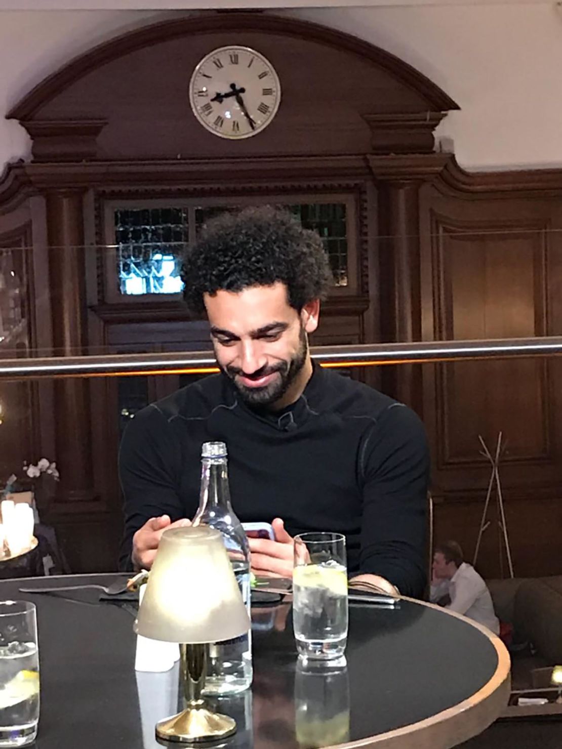 Salah watches a video message from his first coach back in Egypt while waiting for dinner.