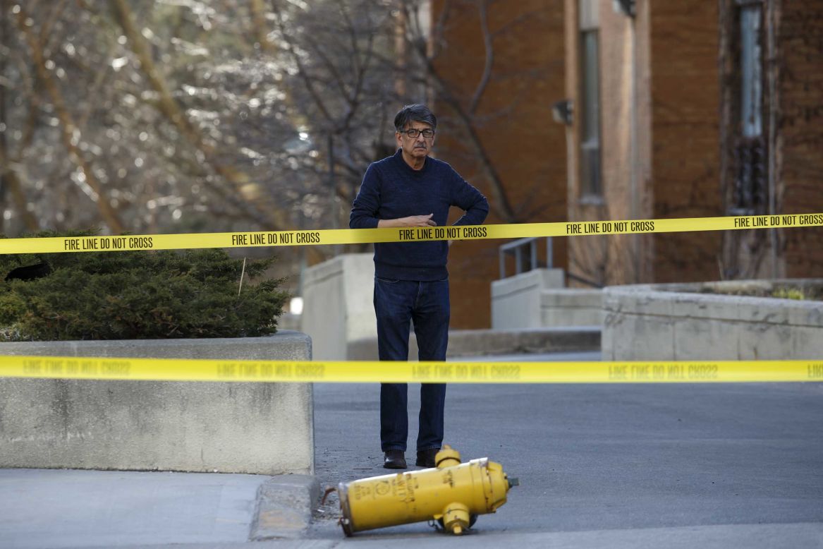 A bystander looks on near a dislodged fire hydrant at the scene.