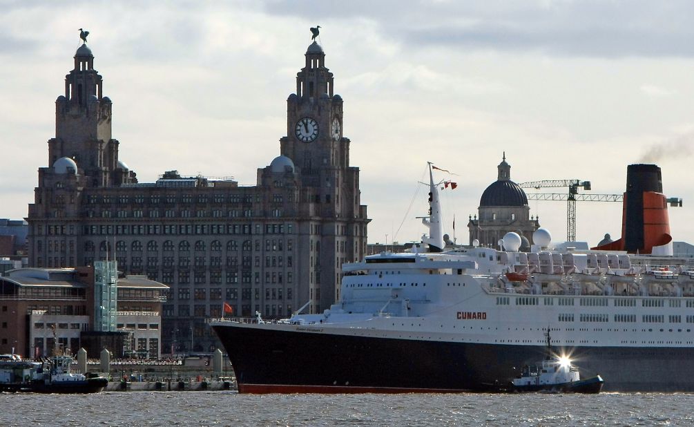 The soon to be decommissioned QE2 docks in front of the Royal Liver Building on the river Mersey, Liverpool, UK, during her farewell voyage in 2008.