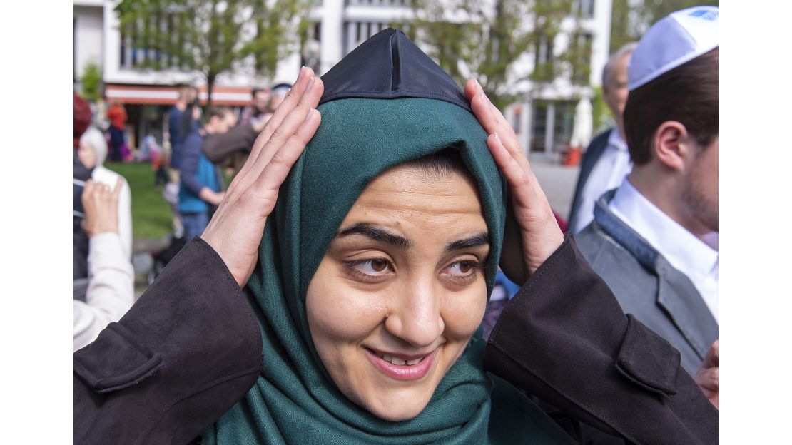A Muslim woman fixes a kippa on her head during a demonstration.