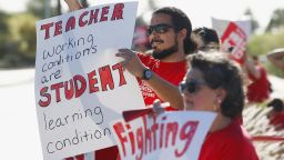 Teachers, parents and students line up along a local street waving to passing vehicles for the latest teacher protest for higher teacher pay and school funding Wednesday, April 25, 2018, in Phoenix. Teachers are scheduled to go on strike Thursday. (AP Photo/Ross D. Franklin)