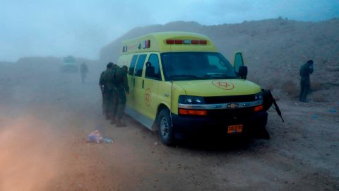 Israeli soldiers and emergency services cover their faces Thursday from the dust from a helicopter.