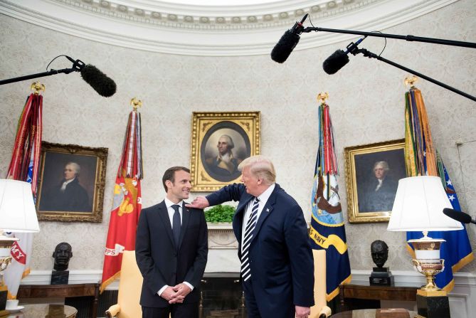 Trump <a target="_blank">jokingly brushes what he described as dandruff</a> from Macron's shoulder on April 24, in the Oval Office.