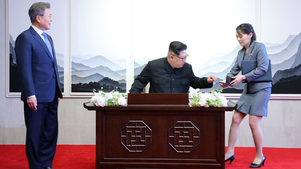North Korea's leader Kim Jong Un (C) prepares to sign the guest book next to his sister Kim Yo Jong during the Inter-Korean summit with South Korea's President Moon Jae-in (L) at the Peace House building on the southern side of the truce village of Panmunjom, April 27, 2018.