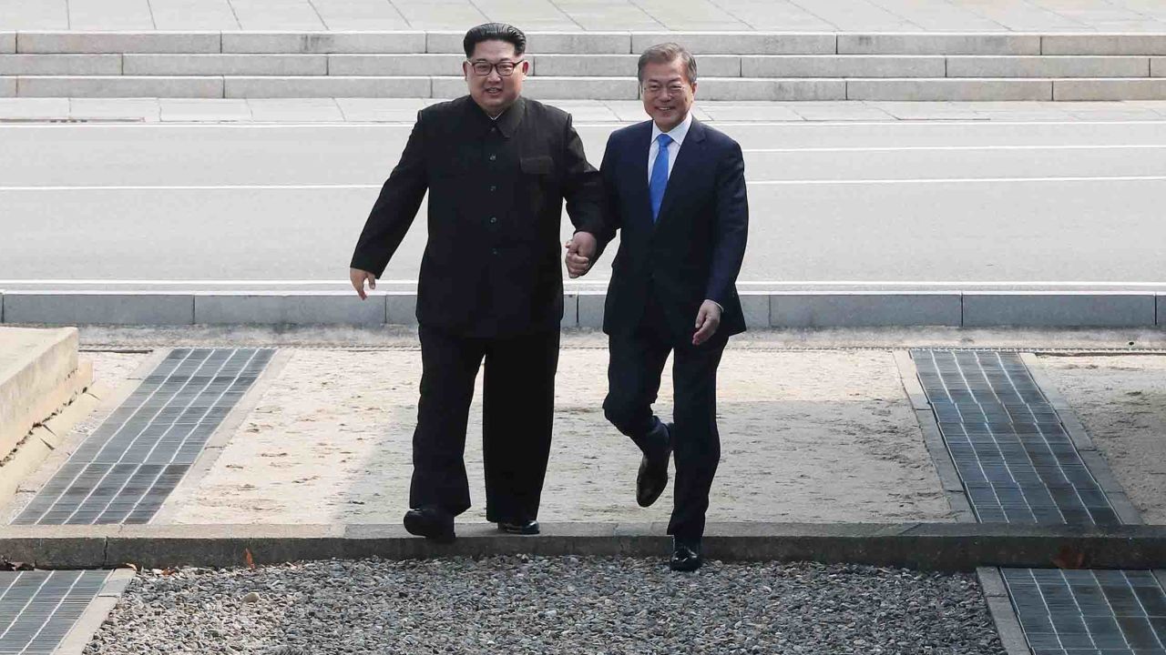 TOPSHOT - North Korea's leader Kim Jong Un (L) steps with South Korea's President Moon Jae-in (R) across the Military Demarcation Line that divides their countries ahead of their meeting at the official summit Peace House building at Panmunjom on April 27, 2018. - North Korean leader Kim Jong Un and the South's President Moon Jae-in sat down to a historic summit Friday after shaking hands over the Military Demarcation Line that divides their countries in a gesture laden with symbolism. (Photo by Korea Summit Press Pool / Korea Summit Press Pool / AFP)        (Photo credit should read KOREA SUMMIT PRESS POOL/AFP/Getty Images)