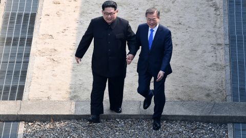 North Korean leader Kim Jong Un (L) and South Korean President Moon Jae-in hold hands as they cross the Military Demarcation Line at the DMZ on April 27.