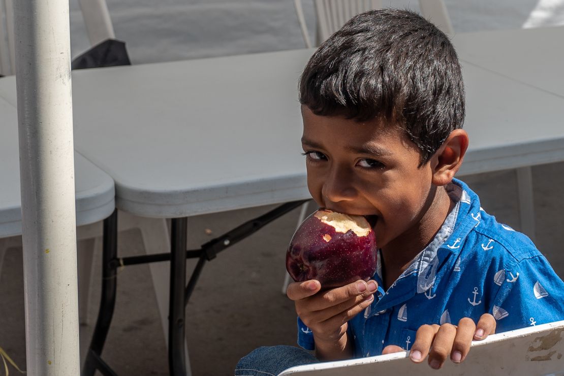 Omar eats an apple. It's been hard for the family to get enough nutritious food. 