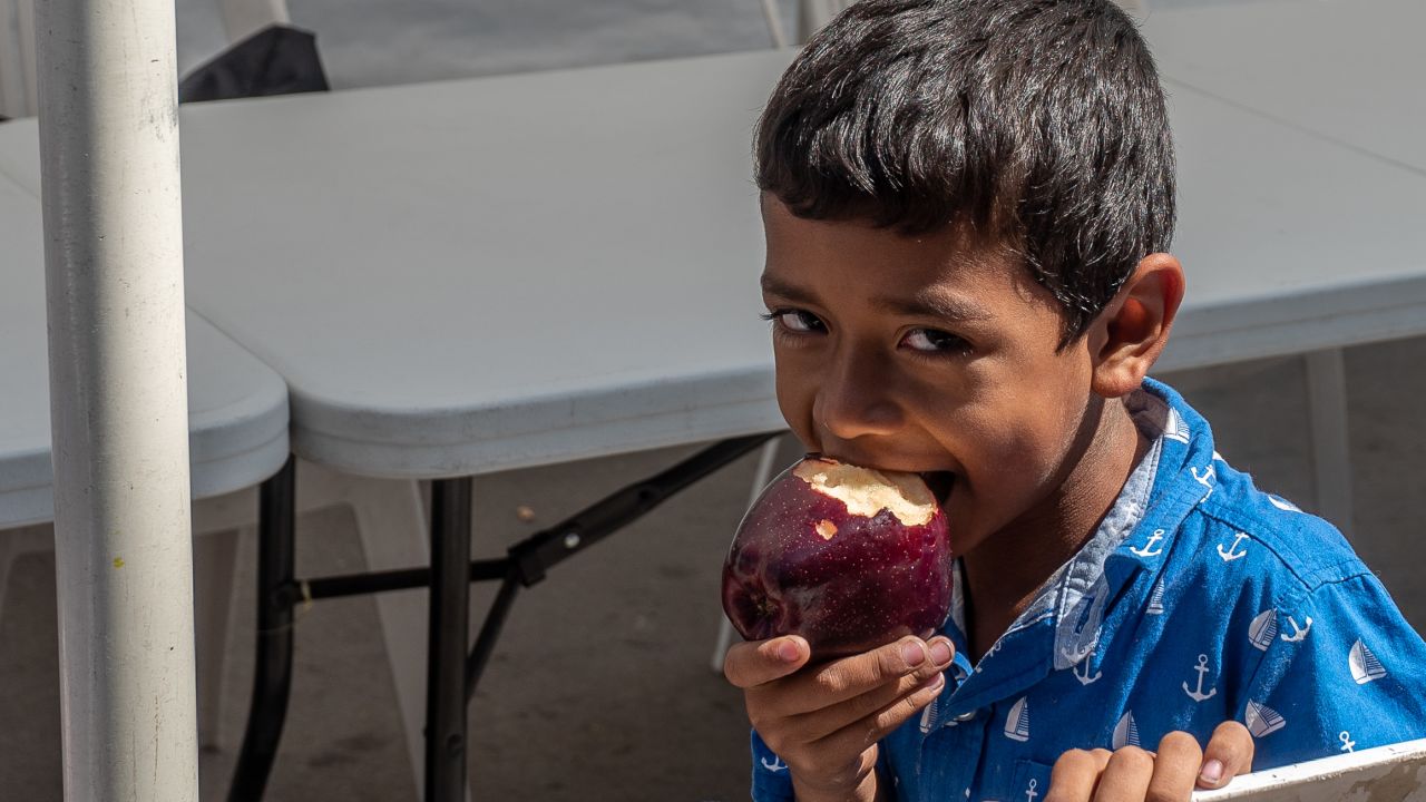 Omar eats an apple. It's been hard for the family to get enough nutritious food.