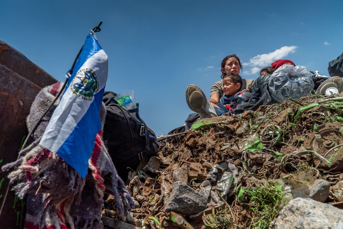 The family sits on top of a load of trash being carried on a freight train taking them north.