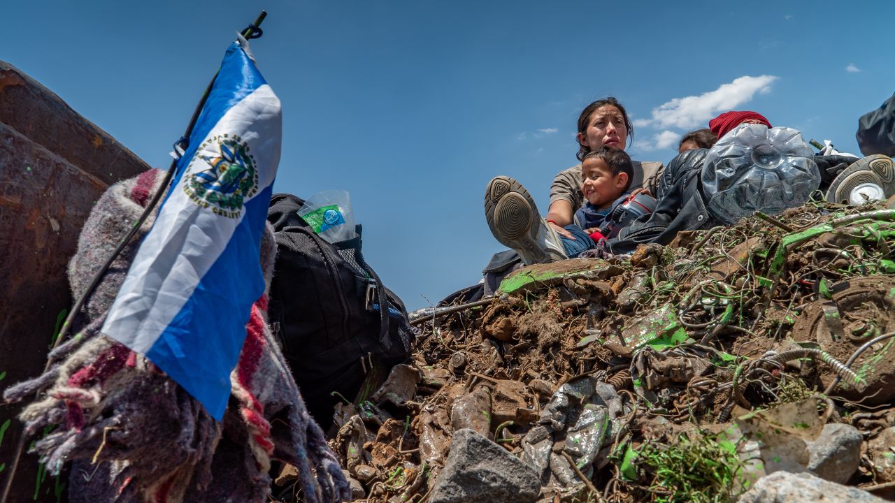 The family sits on top of a load of trash being carried on a freight train taking them north.