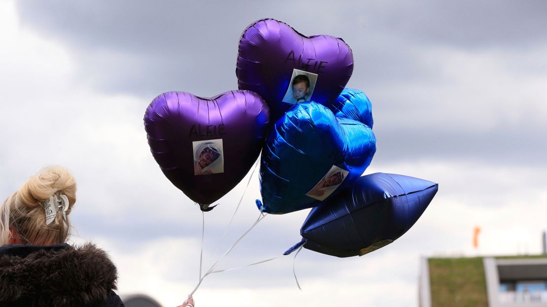 A woman holds balloons with photos of Alfie Evans on Saturday.