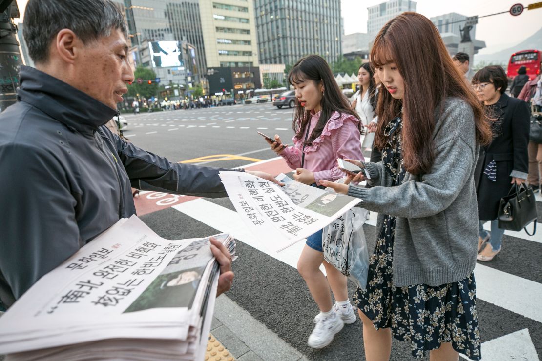 A commuter in Seoul picks up a copy of an extra edition of the Munhwa Ilbo newspaper featuring an image of Moon and Kim on Friday. 