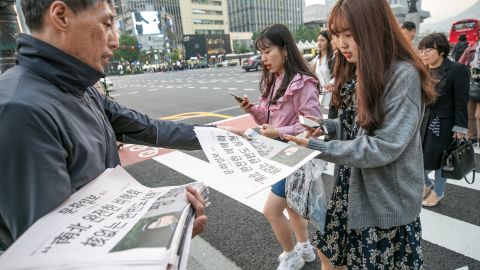 A commuter in Seoul picks up a copy of an extra edition of the Munhwa Ilbo newspaper featuring an image of Moon and Kim on Friday. 