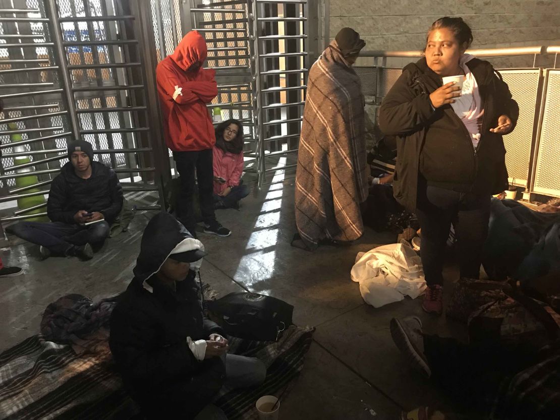 Migrants wait at the US-Mexico border to have their asylum claims processed. America lies on the other side of the turnstiles.