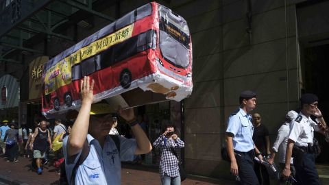 A protester raises a model of a bus, during a rally in Hong Kong calling for better labor conditions.