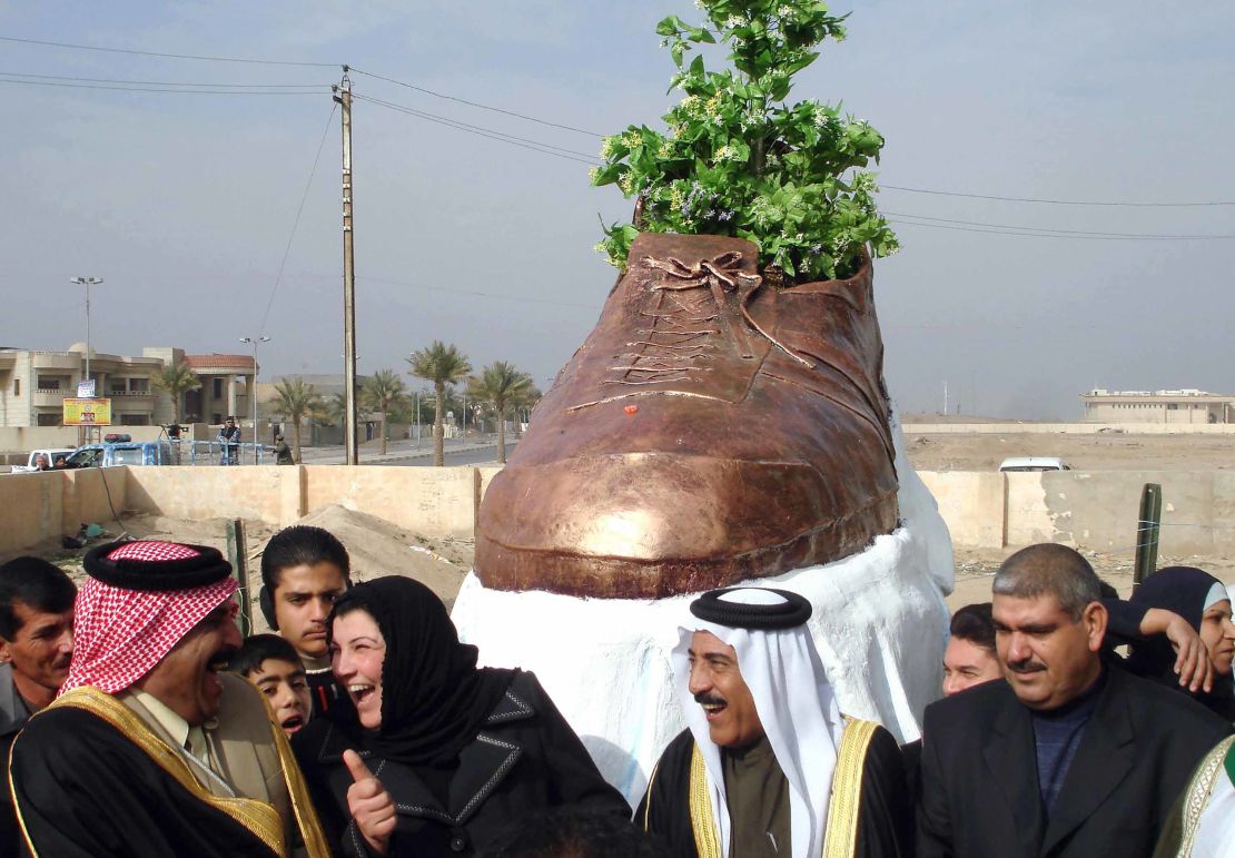 Iraqi officials share a laugh as they unveil a bronze shoe monument representing the one thrown by al-Zaidi at former US president George W. Bush.