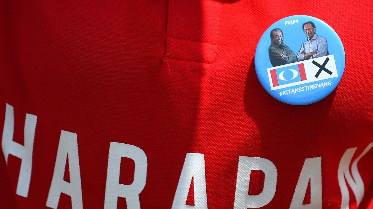 A supporter wears a badge with photographs of former Malaysian prime minister and opposition party Pakatan Harapan's prime ministerial candidate Mahathir Mohamad and jailed former opposition leader Anwar Ibrahim.