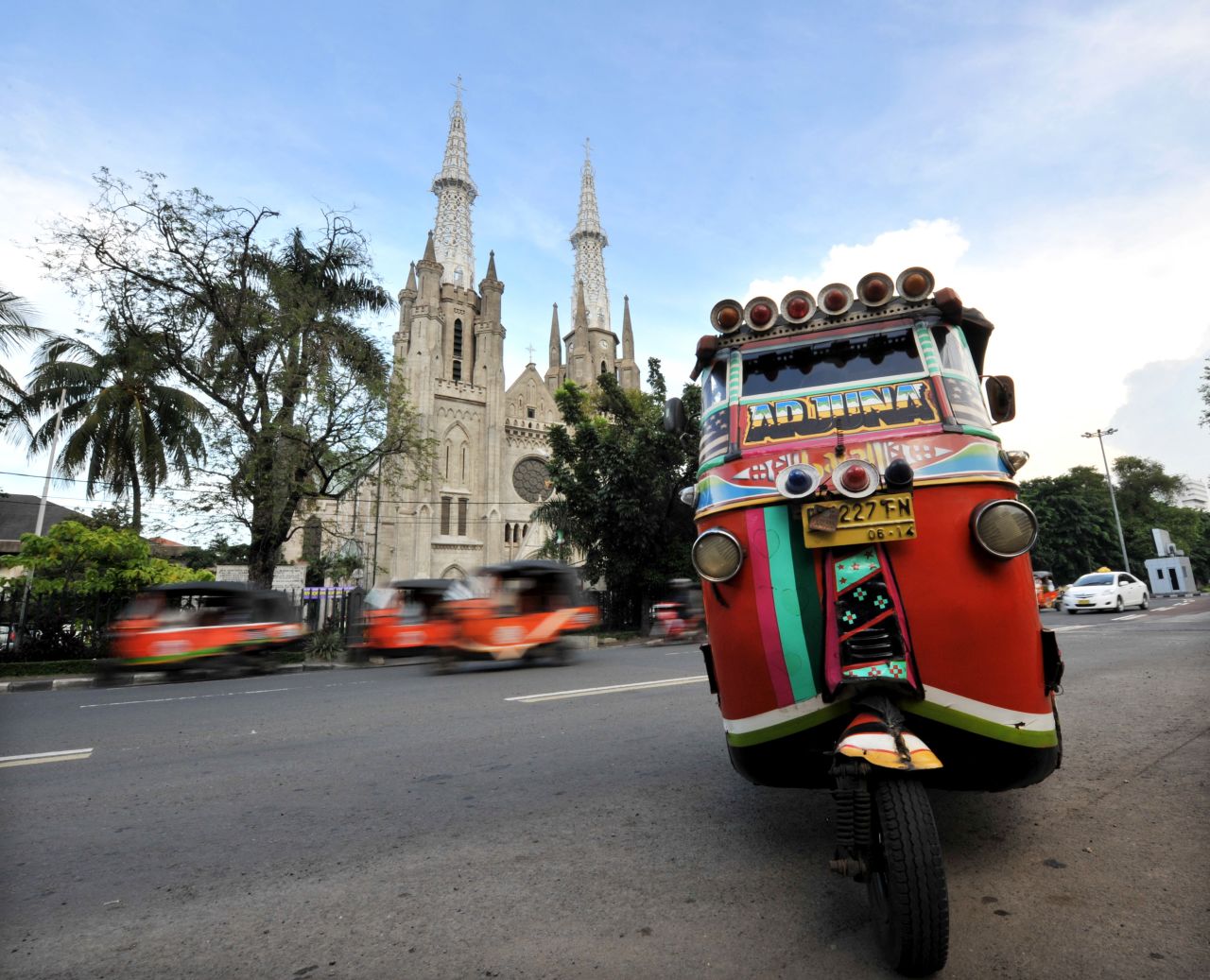 A bajaj is parked in front of the St. Mary of the Assumption Cathedral in Jakarta.