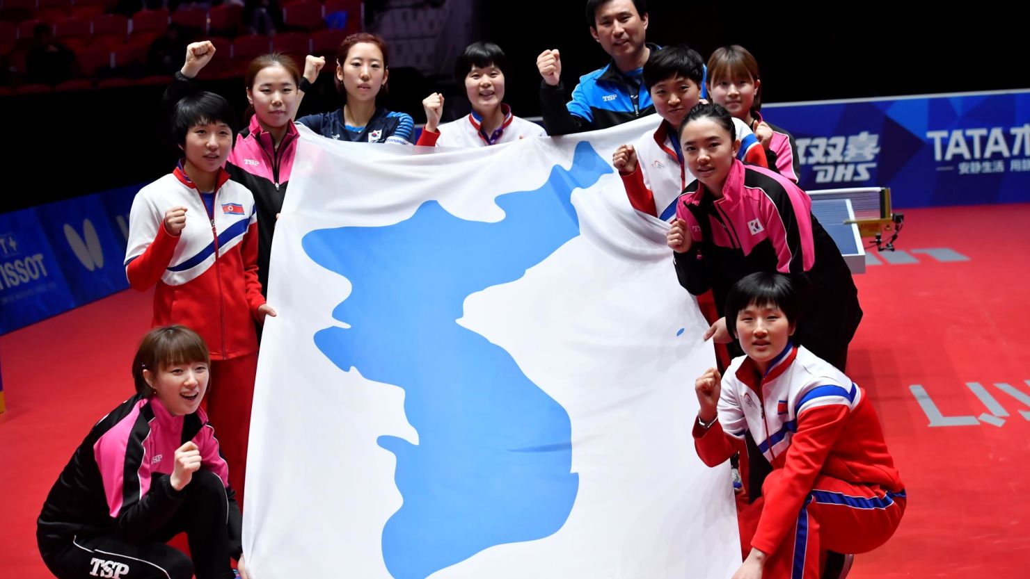 Staff members and players from both South Korea and North Korea pose with a flag.