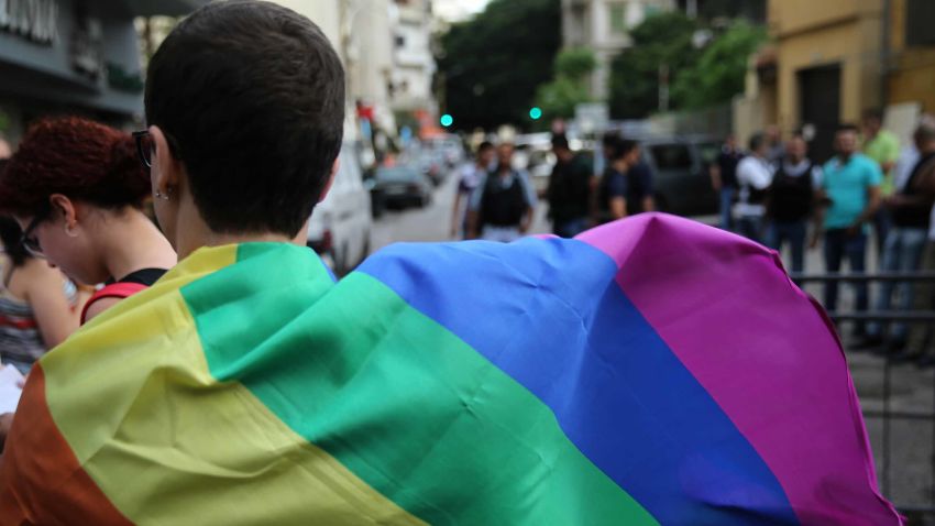 A protester covers his back with a rainbow flag during a sit-in to protest the ongoing criminalization of homosexuality and arbitrary arrests, in front of Hobeich Police Station, where protesters say four men are being held for homosexuality, in Beirut, Lebanon, Sunday, May 15, 2016. (AP Photo/Hussein Malla)