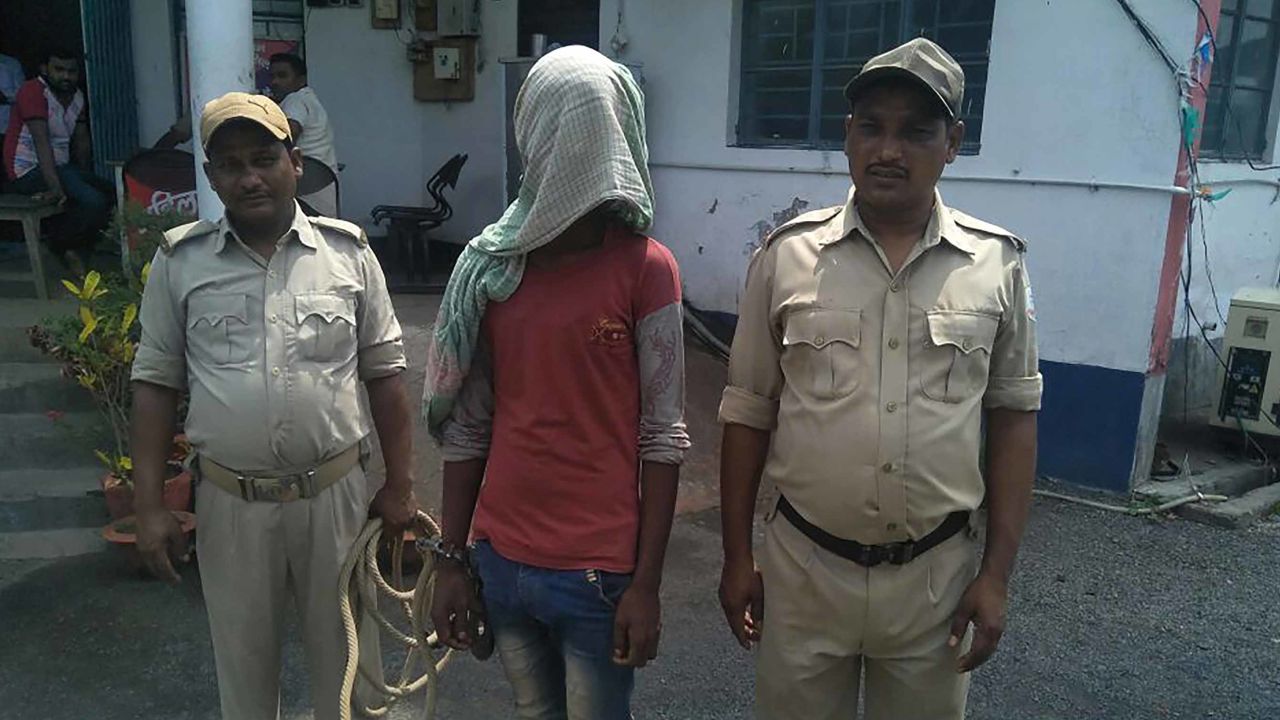 A suspect (C) being held by Indian police in the case of a 17-year-old girl who was raped and set on fire.