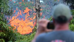 TOPSHOT - A man watches as lava is seen sewing from a fissure in the Leilani Estates subdivision near the town of Pahoa on Hawaii's Big Island on May 4, 2018 as up to 10,000 people were asked to leave their homes following the eruption of the Kilauea volcano that came after a series of recent earthquakes. (Photo by Frederic J. BROWN / AFP)        (Photo credit should read FREDERIC J. BROWN/AFP/Getty Images)