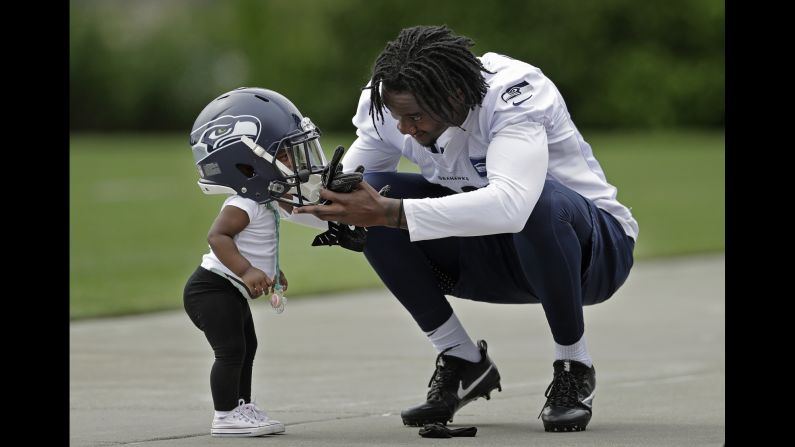 Seattle cornerback Tre Flowers puts his helmet on his 1-year-old daughter, Bailee, after attending rookie camp on Friday, May 4.