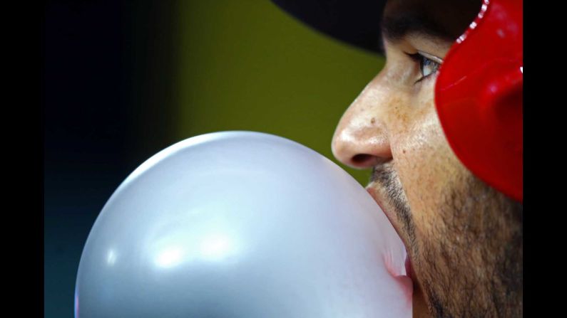Cincinnati third baseman Eugenio Suarez blows a giant bubble as he stands on the dugout steps on Tuesday, May 1.