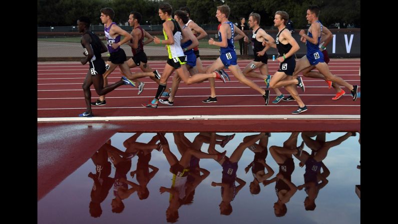 Collegiate runners are reflected by a water obstacle during a race in Stanford, California, on Thursday, May 3.