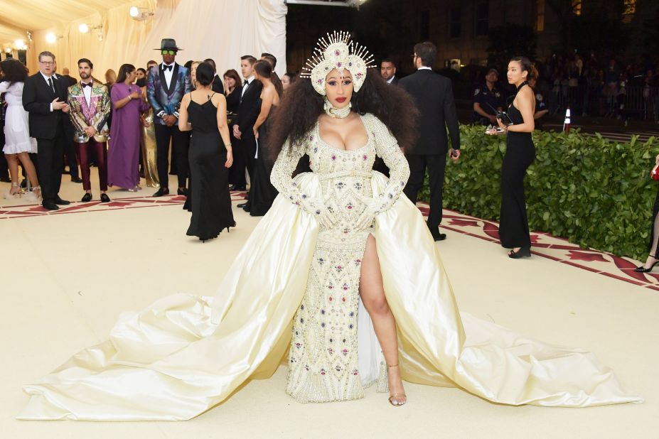 Cardi B wears an intricate headpiece and shimmering gown and train. She was joined by designer Jeremy Scott on the carpet. <br />