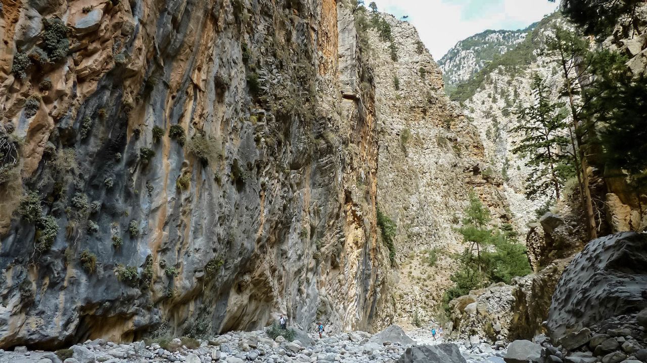 Hikers are dwarfed by the ravine walls towering above. 