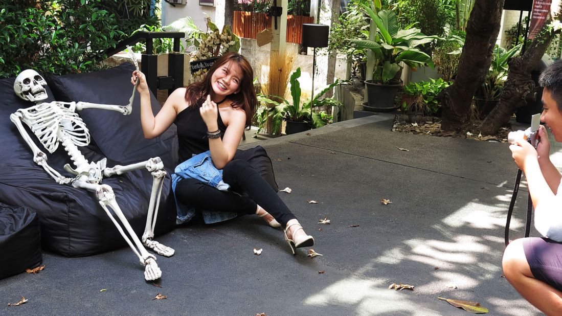 <strong>'I don't want to die': </strong>Angie, a 20-year-old student, poses next to the cafe's resin skeleton but won't go inside the coffin "because I don't want to die now."