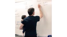 professor holds baby while teaching